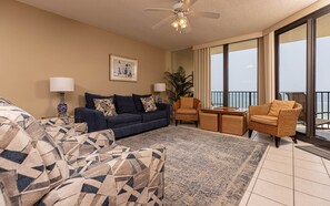 A living room with a sofa, armchairs, a coffee table, and a balcony with a view. - Phoenix Viii 81103 3 Bedroom Condo (Orange Beach)