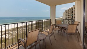 Ein Balkon mit Gartenmöbeln mit Blick auf Strand und Meer.