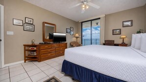 A hotel room with a large bed, a dresser, a television, and a balcony with a view. - Phoenix Viii 81103 3 Bedroom Condo (Orange Beach)