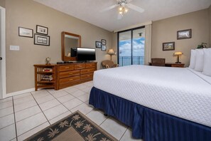 A hotel room with a large bed, a dresser, a television, and a balcony with a view. - Phoenix Viii 81103 3 Bedroom Condo (Orange Beach)