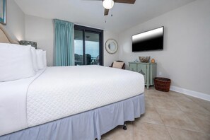 A bedroom with a large bed, a ceiling fan, a television, and a view of the outside. - Phoenix Vii 7912 3 Bedroom Condo (Orange Beach)