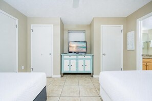 Een hotelkamer met twee bedden, een klein kastje met een televisie en een badkamer zichtbaar door een glazen deur.