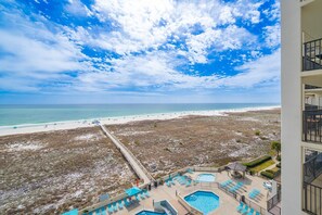 A beach view from a balcony with a pool and lounge chairs. - Phoenix Vii 7709 2 Bedroom Condo (Orange Beach)