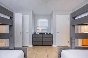 Una habitación con literas, un aparador, un televisor y una ventana.