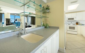 A modern kitchen with a large island, white cabinetry, and a glass backsplash. - Phoenix Viii 8606 3 Bedroom Condo (Orange Beach)