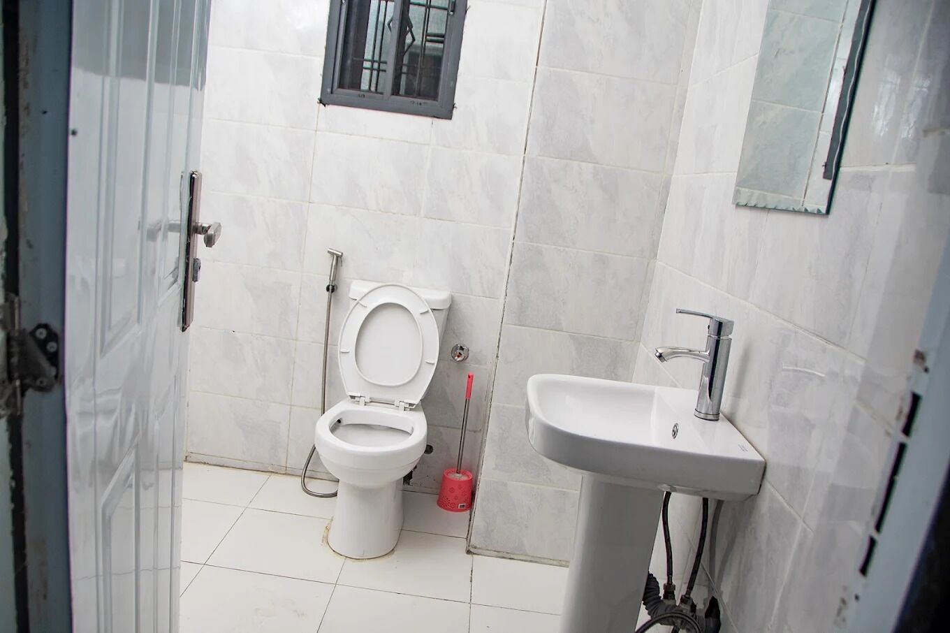 A bathroom with a toilet, a sink, and a window.