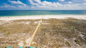 A beach with a sandy shore, a clear sky, and a distant view of the ocean. - Phoenix Vii 71205 3 Bedroom Condo (Orange Beach)