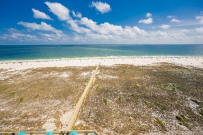 A beach with a sandy shore, a clear sky, and a distant view of the ocean. - Phoenix Vii 71205 3 Bedroom Condo (Orange Beach)
