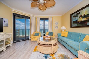 A living room with a sofa, chairs, a coffee table, a ceiling fan, and a balcony with a view. - Phoenix Vii 71205 3 Bedroom Condo (Orange Beach)
