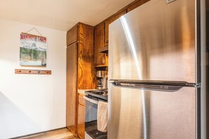 A kitchen with a stainless steel refrigerator, wooden cabinets, and a coffee maker. - Cozy Ski Retreat! 2BR/2BA | Walk to Canyon Lodge! (Mammoth Lakes)