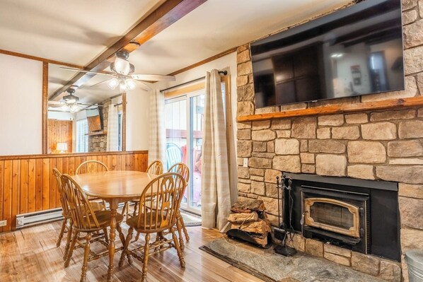 A dining area with a stone fireplace, wooden dining table, and chairs. - Cozy Ski Retreat! 2BR/2BA | Walk to Canyon Lodge! (Mammoth Lakes)
