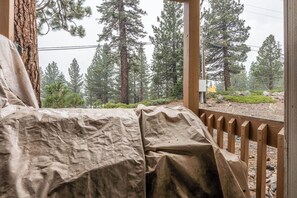 A covered outdoor seating area with a view of a forested landscape. - Cozy Ski Retreat! 2BR/2BA | Walk to Canyon Lodge! (Mammoth Lakes)