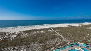 A beach resort with a swimming pool, beach chairs, and a boardwalk. - Phoenix Vii 71213 2 Bedroom Condo (Orange Beach)
