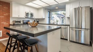 A modern kitchen with a central island, stainless steel appliances, and a view to the outside. - Summer Retreat in Style! Newly Renovated 2BR/3BA (Mammoth Lakes)