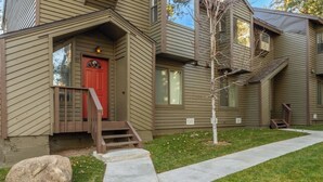 A two-story house with a red door, a small front porch, and a tree in the yard. - Summer Retreat in Style! Newly Renovated 2BR/3BA (Mammoth Lakes)