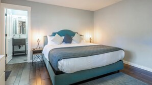 A bedroom with a bed, bedside tables, a nightstand, a mirror, and a bathroom visible through an open door. - Summer Retreat in Style! Newly Renovated 2BR/3BA (Mammoth Lakes)