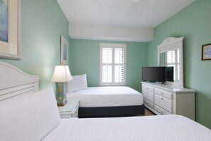 A bedroom with two beds, a TV, a dresser, and a window with shutters. - Phoenix Viii 81106 3 Bedroom Condo (Orange Beach)