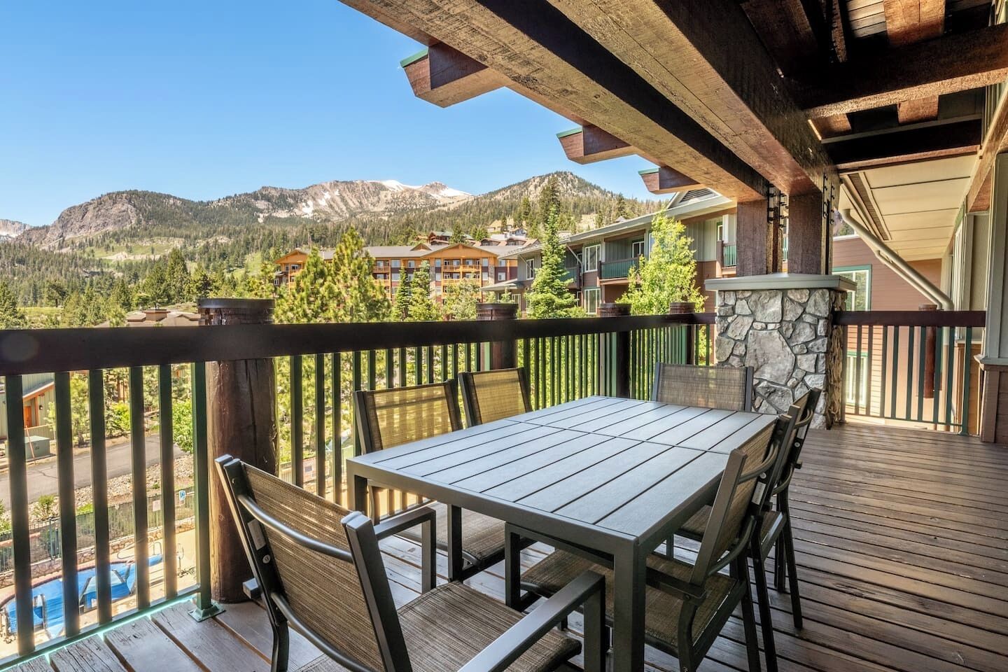 Une terrasse en bois avec une table et des chaises, offrant une vue sur un paysage montagneux.