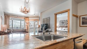Een moderne keuken met een granieten aanrecht, een roestvrijstalen spoelbak en een inbouwvaatwasser.