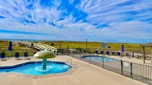 A swimming pool with a unique mushroom-shaped fountain, surrounded by a fence and lounge chairs. - Phoenix Viii 8502 2 Bedroom Condo (Orange Beach)