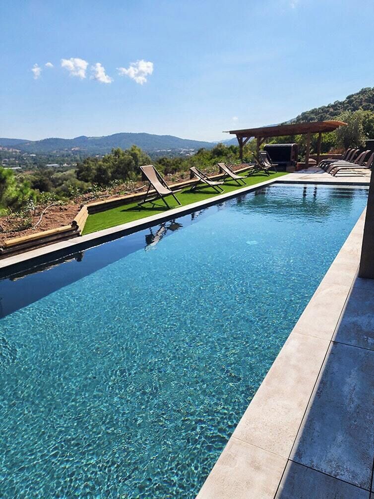 Una piscina rectangular con agua cristalina, rodeada por una solana empavedada.