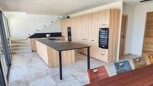 Une cuisine moderne dotée d’un îlot central, de meubles de rangement en bois et d’un escalier menant à un étage supérieur.