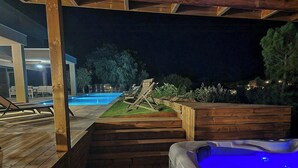 Une terrasse en bois avec un jacuzzi, une piscine et des chaises longues.