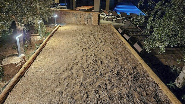 Vue nocturne d’un espace aménagé avec une piscine, des sièges et des allées.