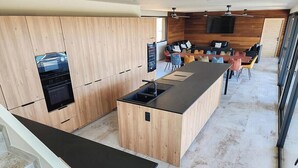 Une cuisine moderne dotée d’un îlot central, de meubles de rangement en bois et d’un four encastré.