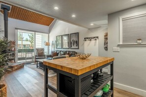 A modern kitchen with a wooden island, a built-in grill, and a dining area with a sofa and a lamp. - Stylish in Central Mammoth! 2 Bed / 2 Bath + Loft (Mammoth Lakes)