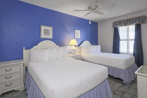 A hotel room with two beds, a ceiling fan, a nightstand with a lamp, and a window with curtains. - Phoenix Viii 81104 3 Bedroom Condo (Orange Beach)