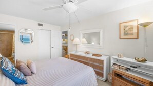 Ein Schlafzimmer mit Bett, Kommode und Deckenventilator.