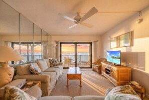 Ein Hotelzimmer mit Balkon, Fernseher und einer Couch.