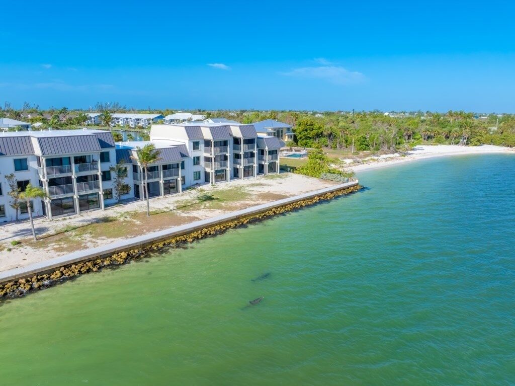 A coastal hotel with multiple-story buildings, a sandy beach, and a clear blue sky.