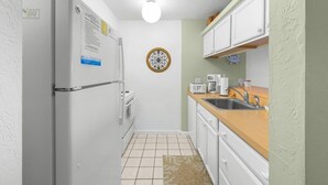 Eine kleine Küche mit Kühlschrank, Backofen, Mikrowelle und Spüle.