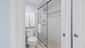 Ein Badezimmer mit Toilette, einer Duschkabine aus Glas und einer weißen Tür.