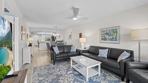 Ein modernes Wohnzimmer mit einer Sofagarnitur, einem Couchtisch und Blick auf die Küche und den Essbereich.