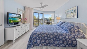 Ein Schlafzimmer mit einem großen Bett, einem Fernseher, einem Balkon mit Blick und einem Deckenventilator.