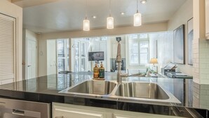 Een moderne keuken met een roestvrijstalen spoelbak, hangende verlichtingsarmaturen en een groot raam.