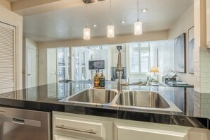 A modern kitchen with a stainless steel sink, overhead pendant lights, and a large window. - Stunning Sunlit & Spacious-1BR/2BTH+Loft (Mammoth Lakes)