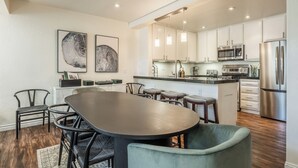 Een moderne keuken met roestvrijstalen apparatuur, een eethoek met een grote tafel en stoelen, en kunstwerken aan de muren.