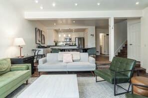 A modern living room with a sofa, chairs, a coffee table, and a kitchen in the background. - Stunning Sunlit & Spacious-1BR/2BTH+Loft (Mammoth Lakes)