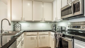 Een moderne keuken met witte kastjes, roestvrijstalen apparatuur en een zwart aanrecht.