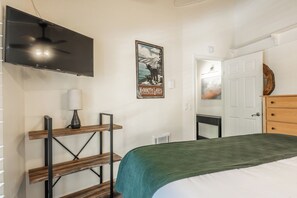 A bedroom with a bed, a TV mounted on the wall, a poster, and a wooden shelf. - Stunning Sunlit & Spacious-1BR/2BTH+Loft (Mammoth Lakes)