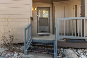 A wooden house entrance with a number '28' sign, a metal gate, and a small porch area with a doormat. - Stunning Sunlit & Spacious-1BR/2BTH+Loft (Mammoth Lakes)