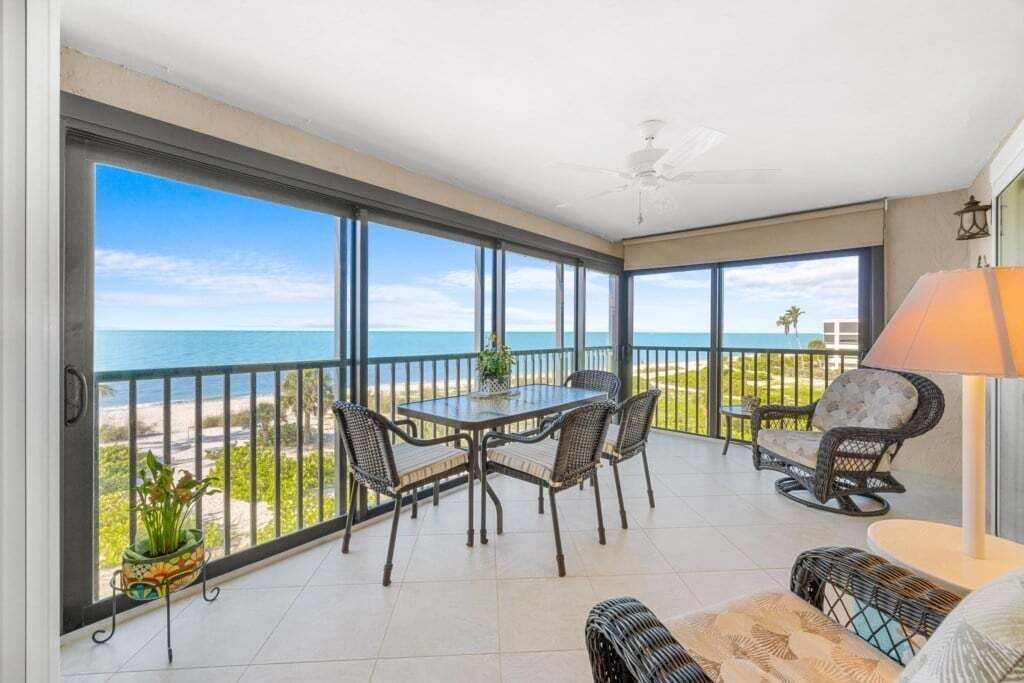A balcony with a table and chairs, a lamp, and a view of the ocean.