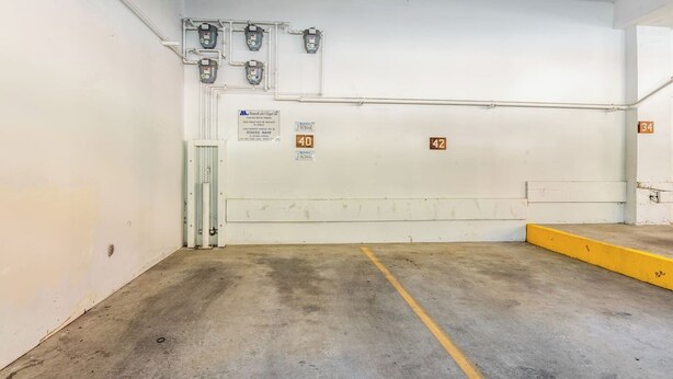 A parking garage with concrete floors, marked parking spaces, and a tow-away sign. - Adventure Basecamp! 1BR + Loft Close to Village (Mammoth Lakes)