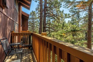 Eine Holzterrasse mit Geländer, einem Tisch und zwei Stühlen.