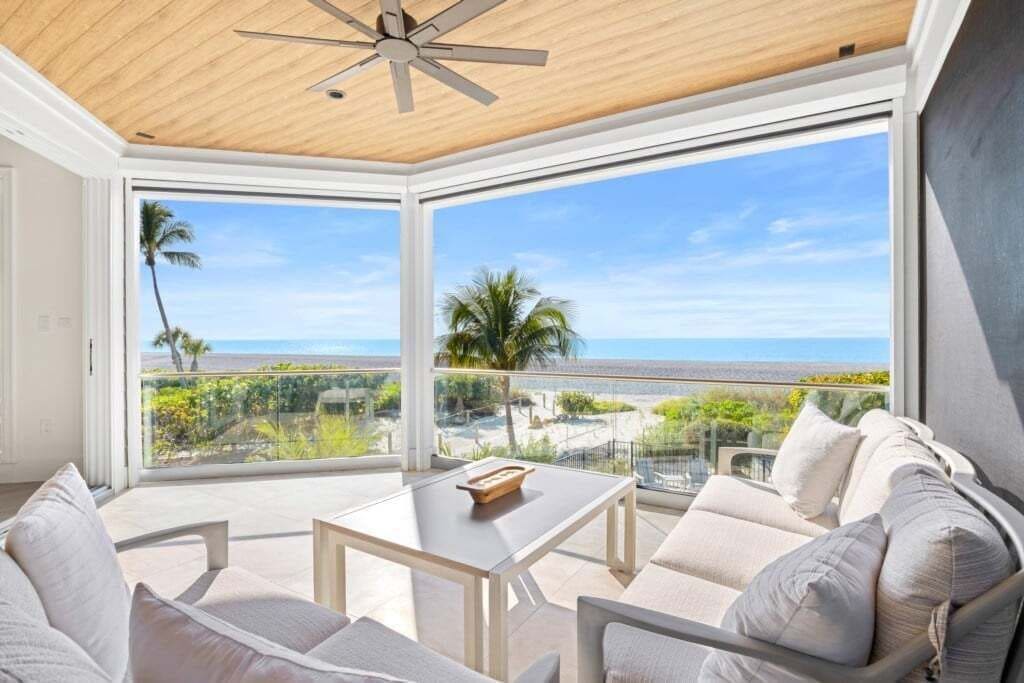 A room with a ceiling fan, a table, and a sofa with cushions.