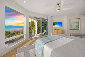 A bedroom with a large bed, a view of the ocean through a sliding door, and a painting on the wall. - Angel's View 4 Bedroom Home (Captiva)